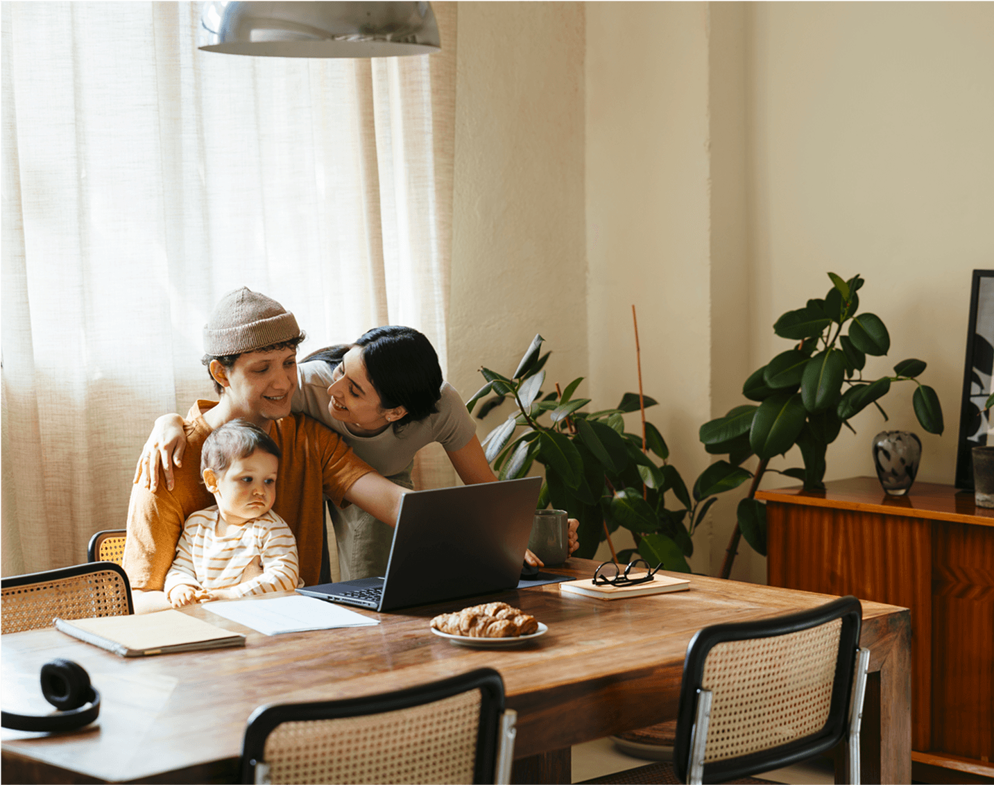 Parents and toddler smiling while looking at a laptop at home